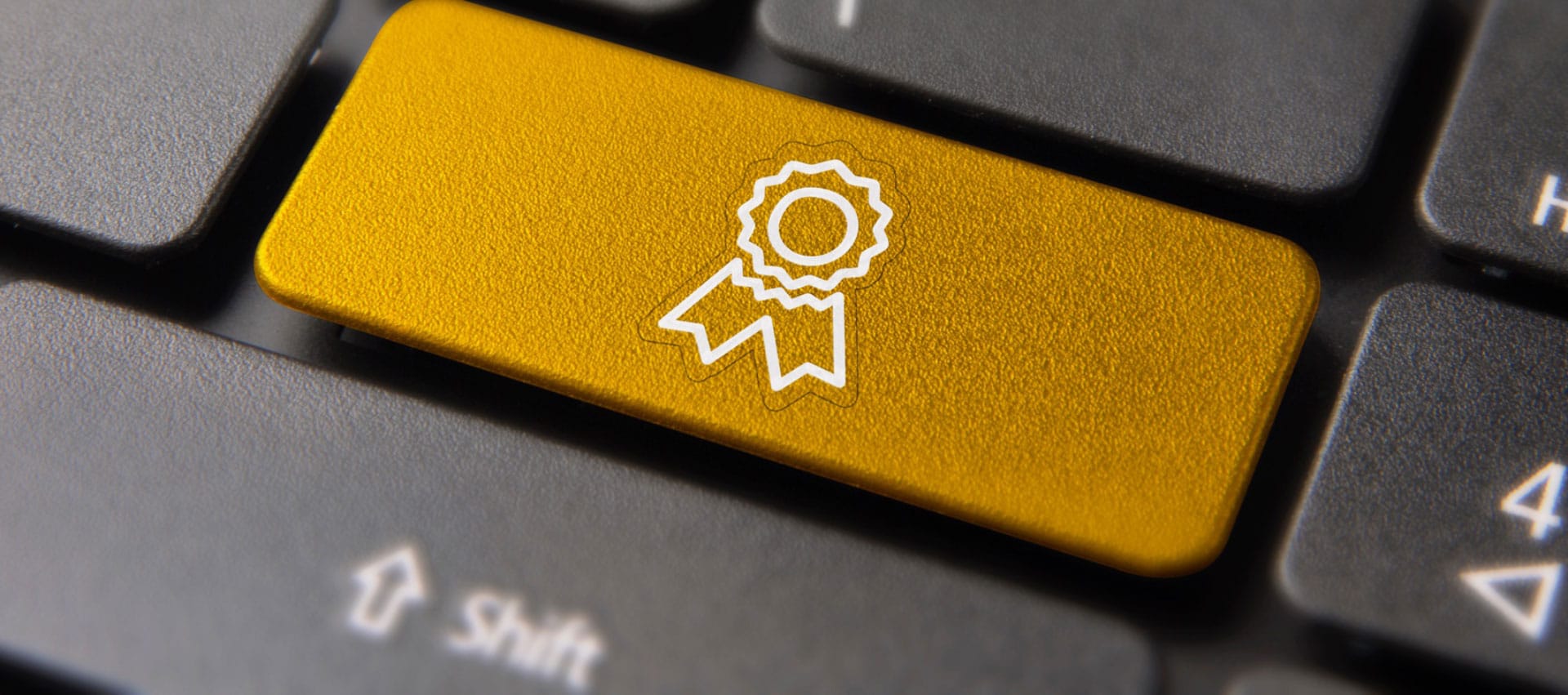 Closeup of black keyboard showcasing one golden key tab with an award graphic